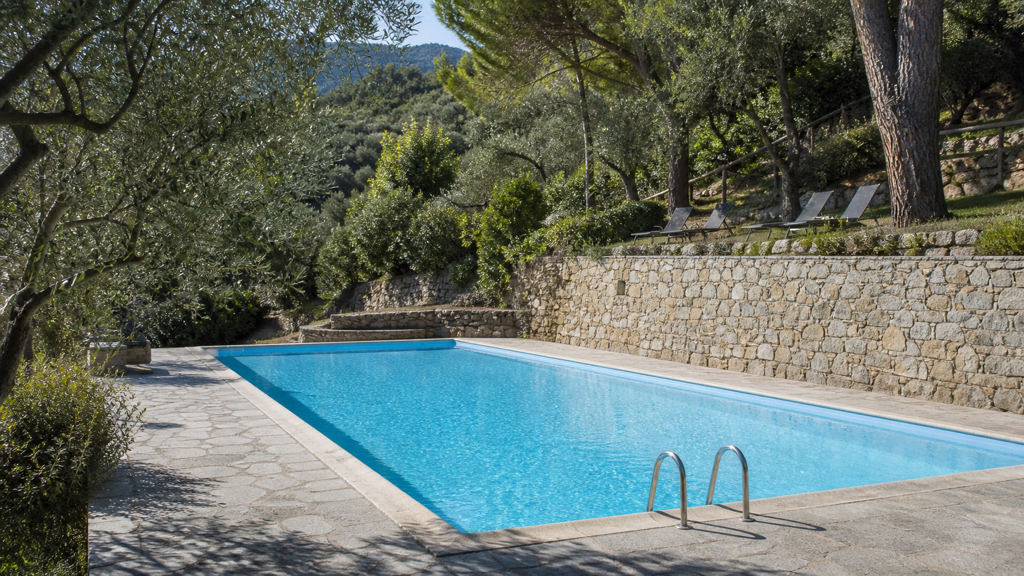 Camping sfeerfoto van een zwembad tussen mediterrane bomen in de Ligurische heuvels