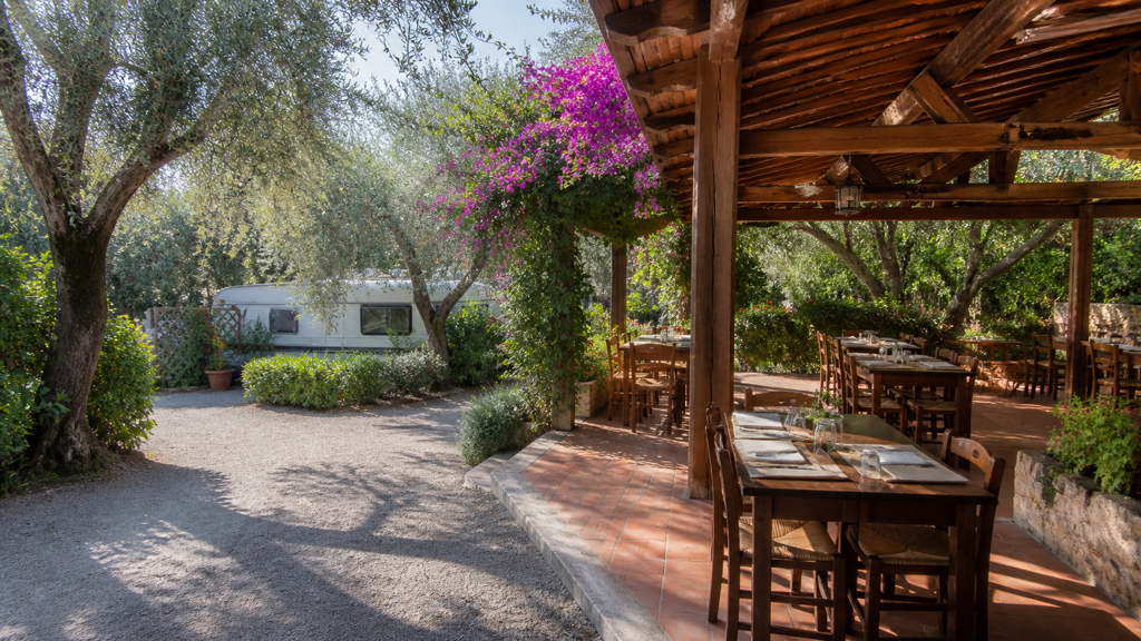 Camping sfeerfoto van een restaurantterras tussen olijfbomen en caravans in Ventimiglia
