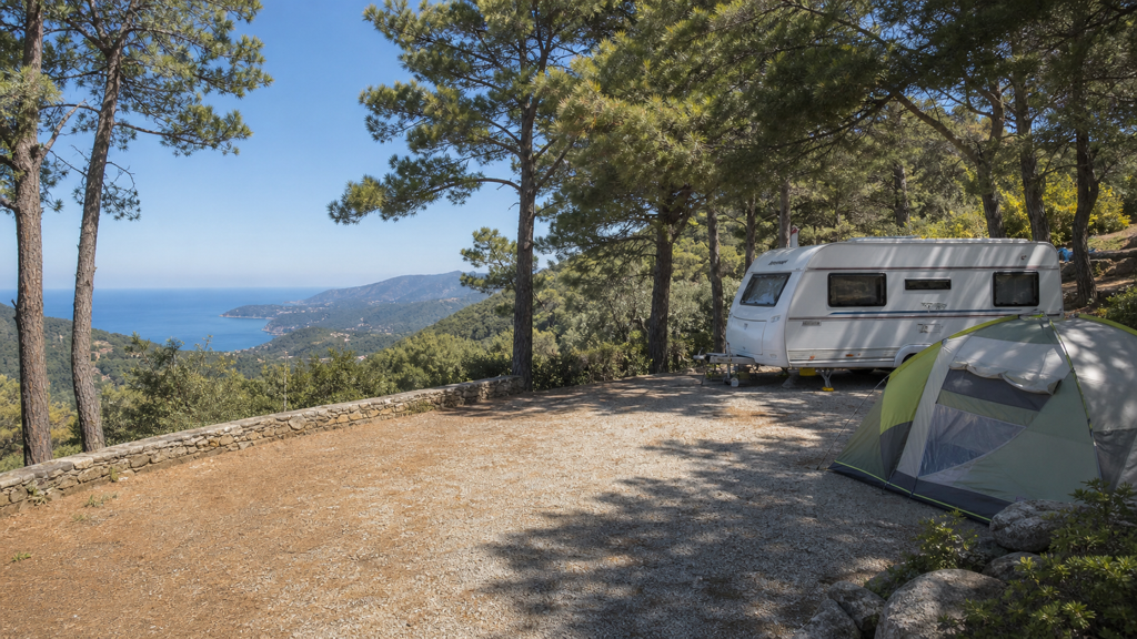 Camping sfeerfoto van een hoger gelegen terras met caravan en uitzicht over Ligurië