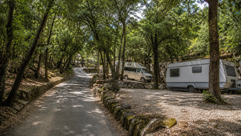 Camping sfeerfoto van schaduwrijke caravanplaatsen langs een boslaan bij Genua