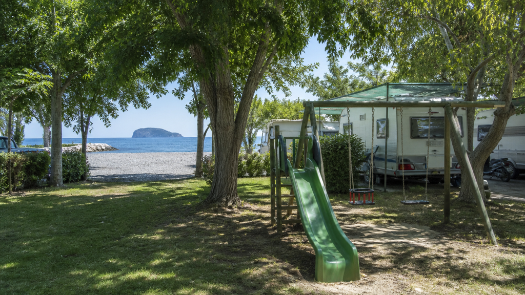 Camping sfeerfoto van een speelplek naast schaduwrijke plaatsen en het kiezelstrand van Albenga